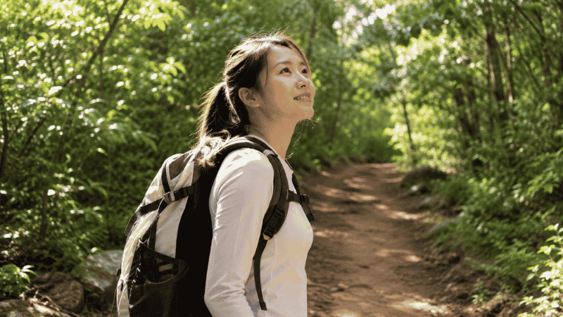 Young beginner hiker with daypack standing at the start of a sunny trail