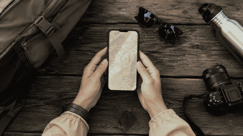 Hiker using a trail map app on smartphone to plan their first hiking route