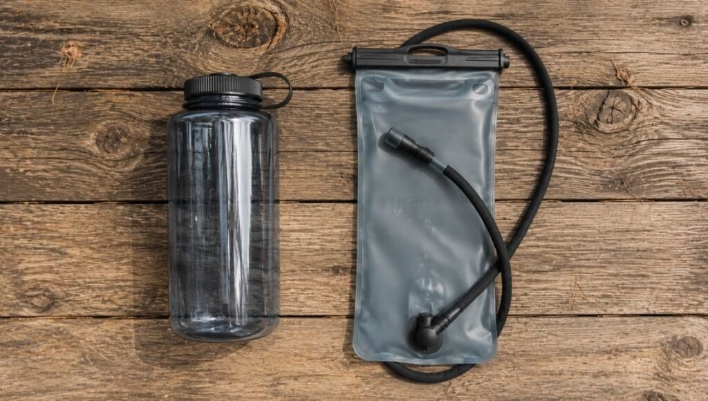 Side-by-side comparison of a wide-mouth hiking water bottle and a hydration bladder with drinking tube showing the difference between the two options for beginner hikers